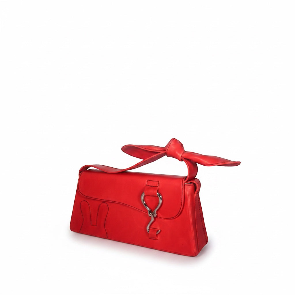 Design Girls World red vegetable-tanned leather mini shoulder bag with a knotted bow strap and bunny logo detail.